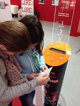 Two people reading a short story in front of a Short Story Dispenser